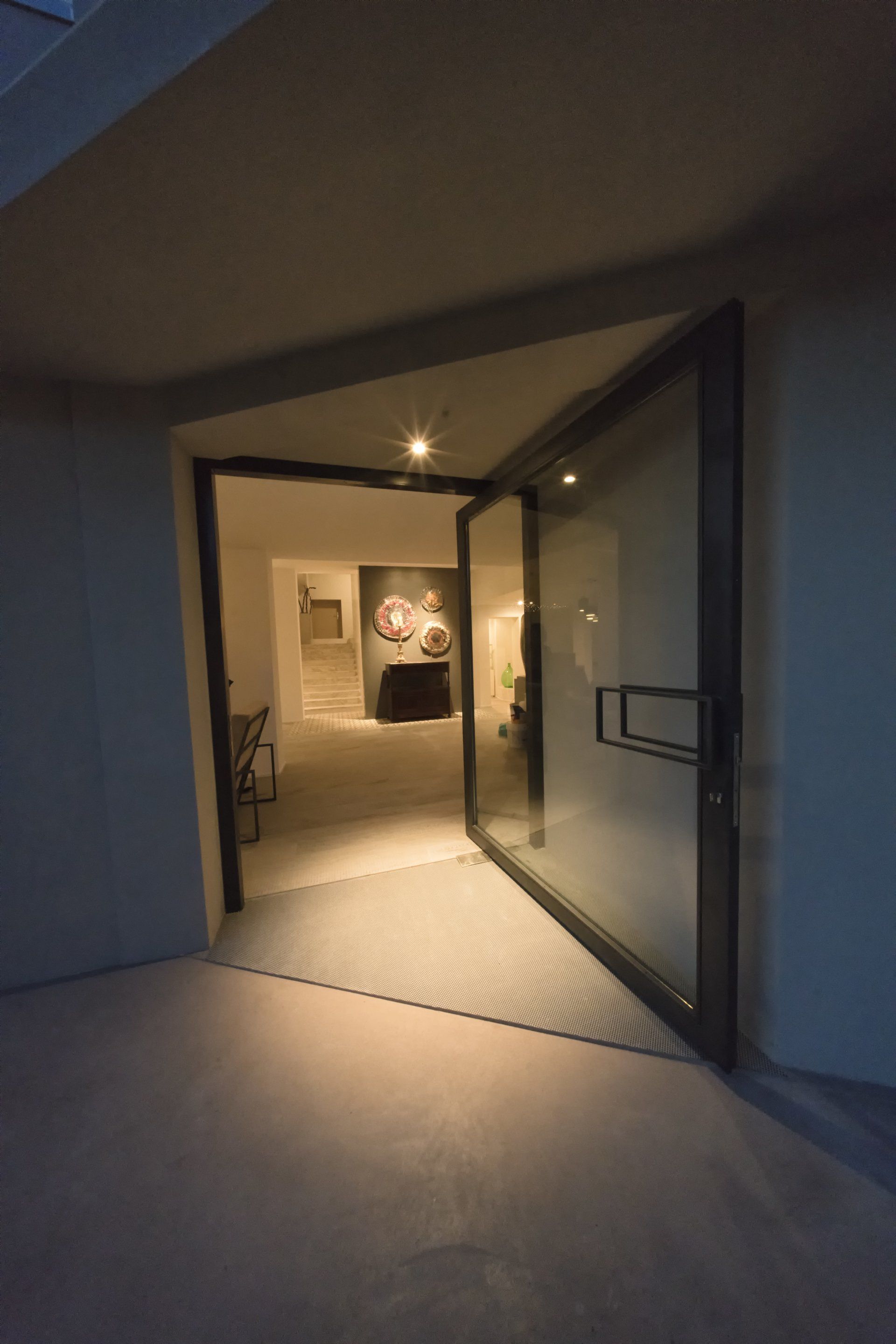 Una porta a vetri aperta rivela una galleria d'arte con dipinti e arredi.