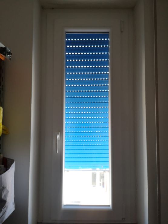 Tenda a rullo blu con telaio bianco.