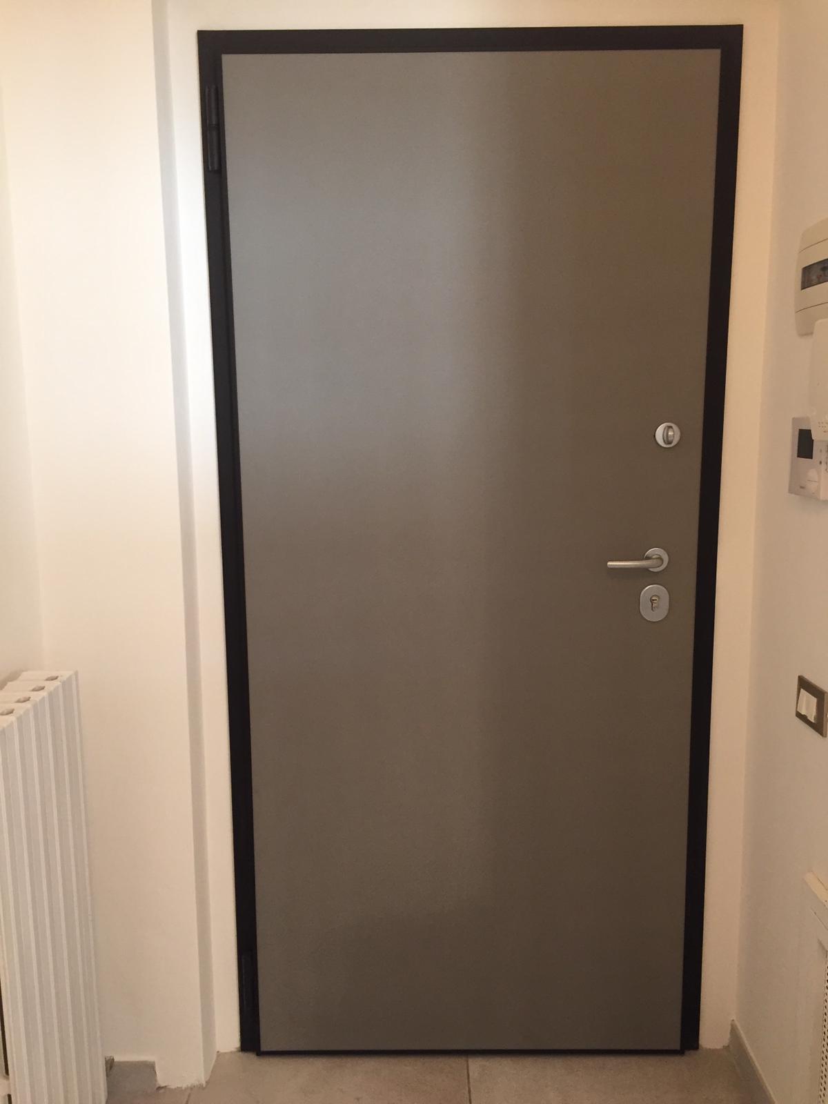 Porta di sicurezza grigia con finiture nere in un corridoio.