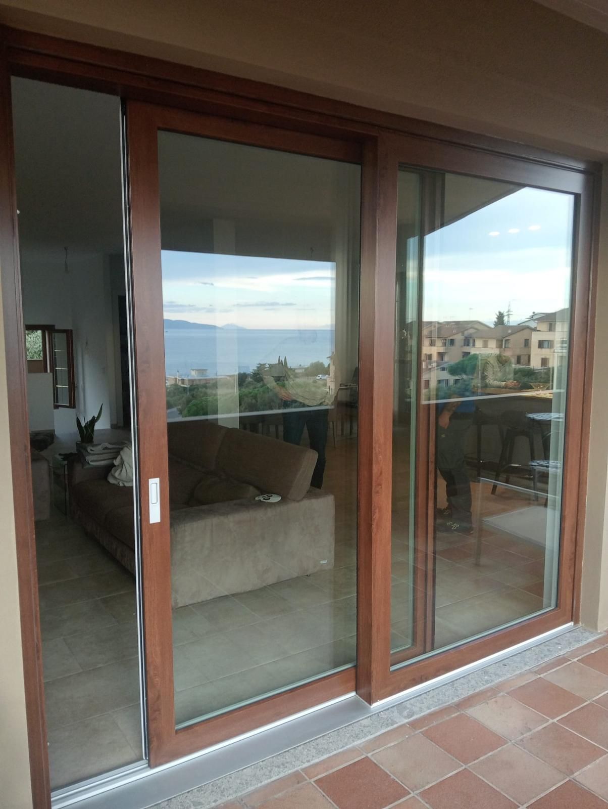 Finestra stretta con la parte inferiore smerigliata, albero visibile all'esterno. Asciugamano bianco appeso al muro.