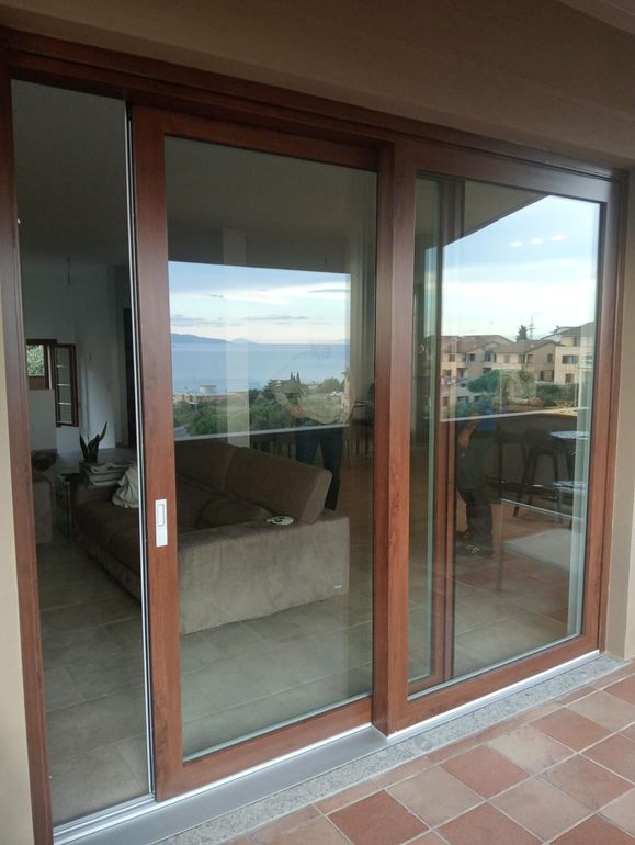 Porte scorrevoli in vetro su una parete bianca che conducono a un'area esterna con piante.