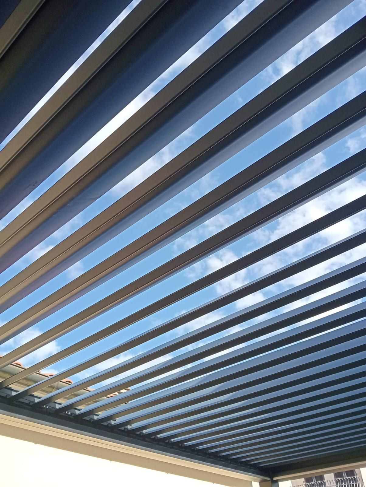 Porta in legno marrone con finestra ad arco in alto, incastonata in una facciata in pietra. Un'auto è parcheggiata sulla destra.