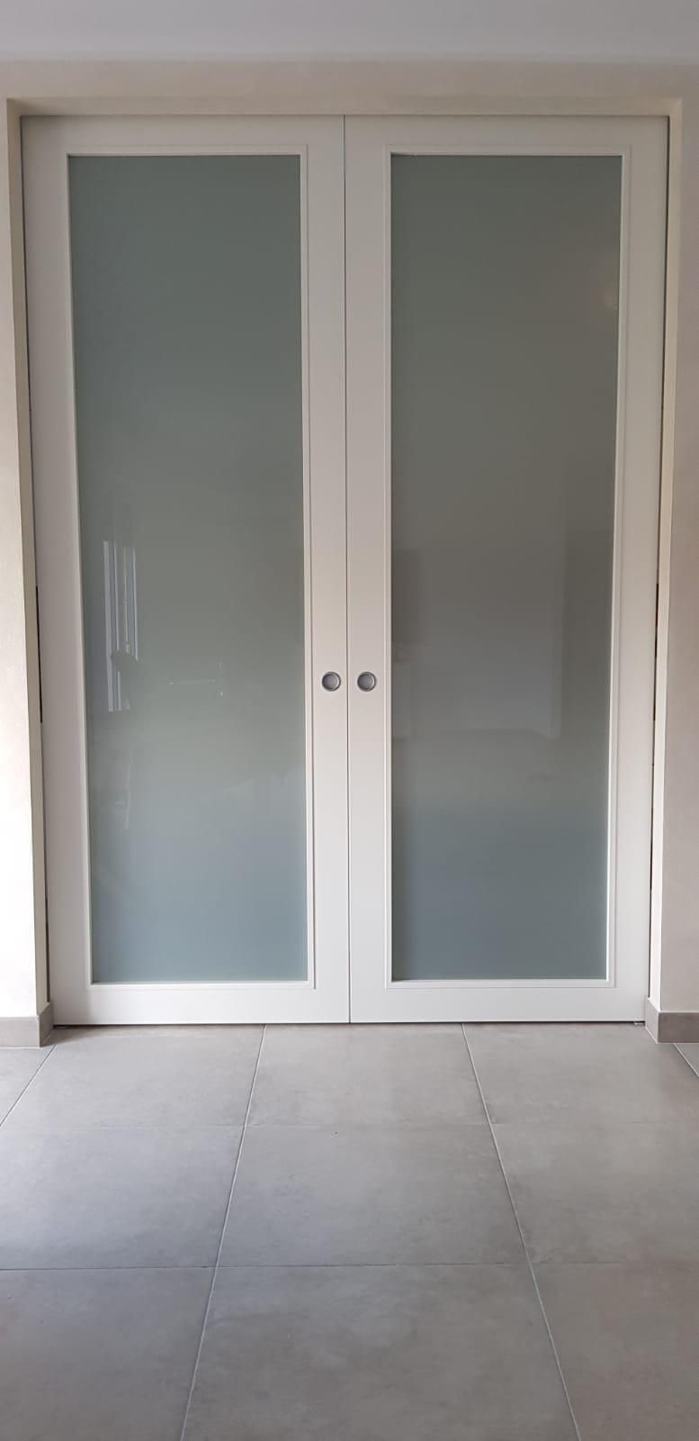 Porta di legno marrone in un corridoio, piccolo termosifone bianco, telefono alla parete, quadri alla parete.