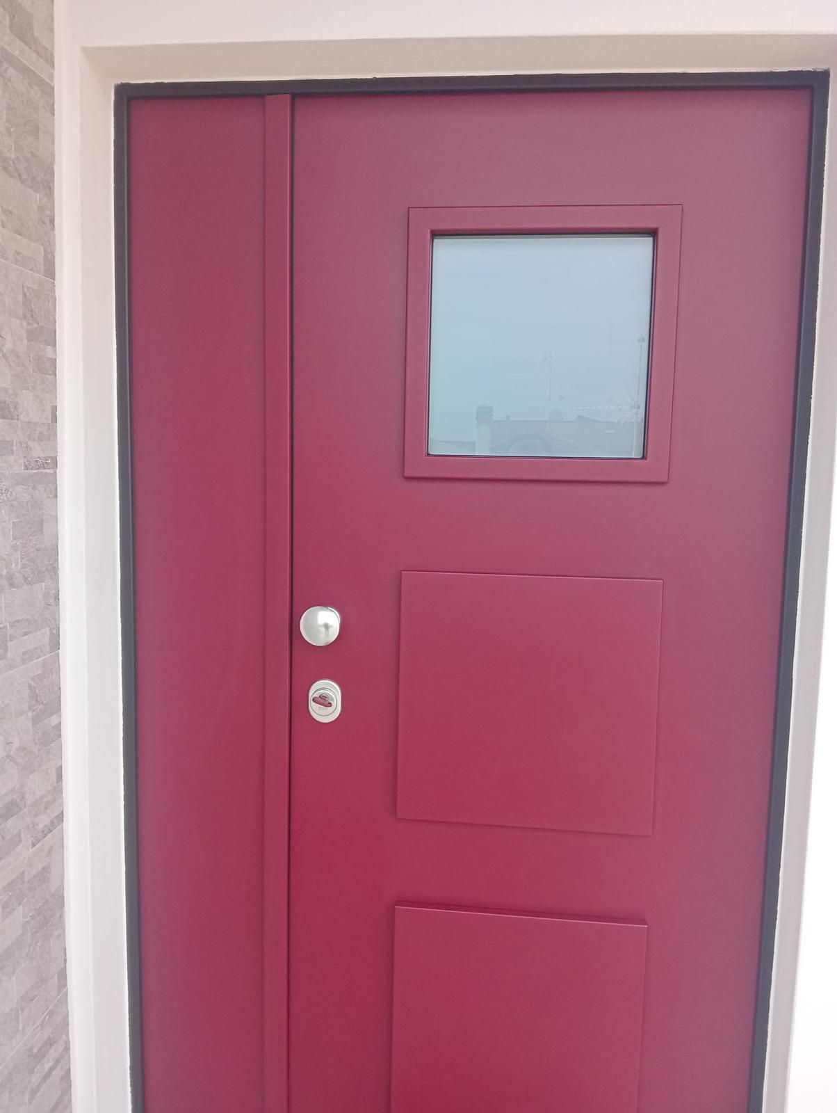 Doppie porte marroni con finestra ad arco, inserite in una cornice di mattoni, contro un muro di pietra.