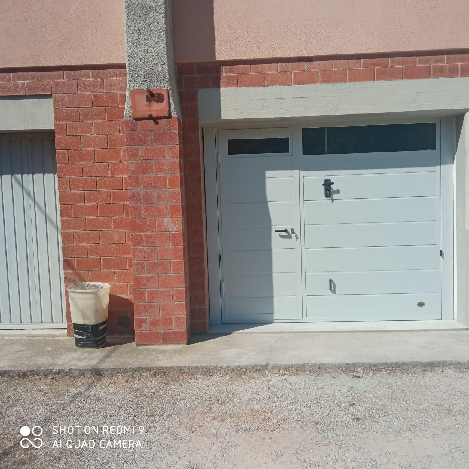 Esterno dell'edificio in pietra con porta e finestra ad arco, finiture in mattoni. Area sottostante pavimentata.