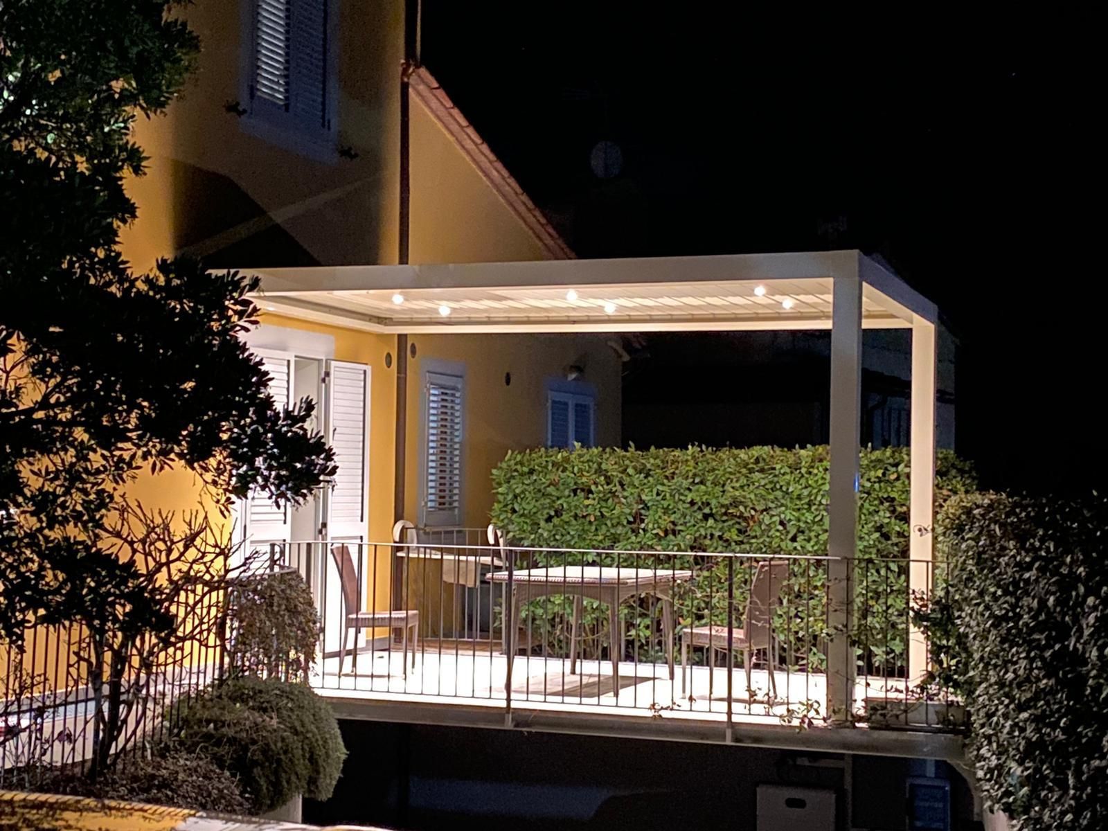 Pergola bianca sopra un patio con tavolo e sedie, con vista sulle montagne.