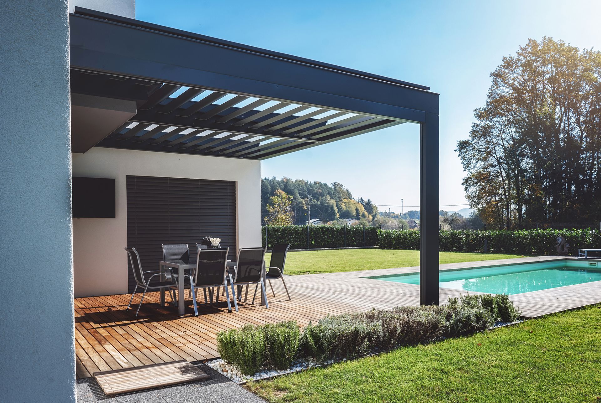 Patio con pergolato, tavolo da pranzo e piscina nel cortile sul retro. Luce solare intensa.