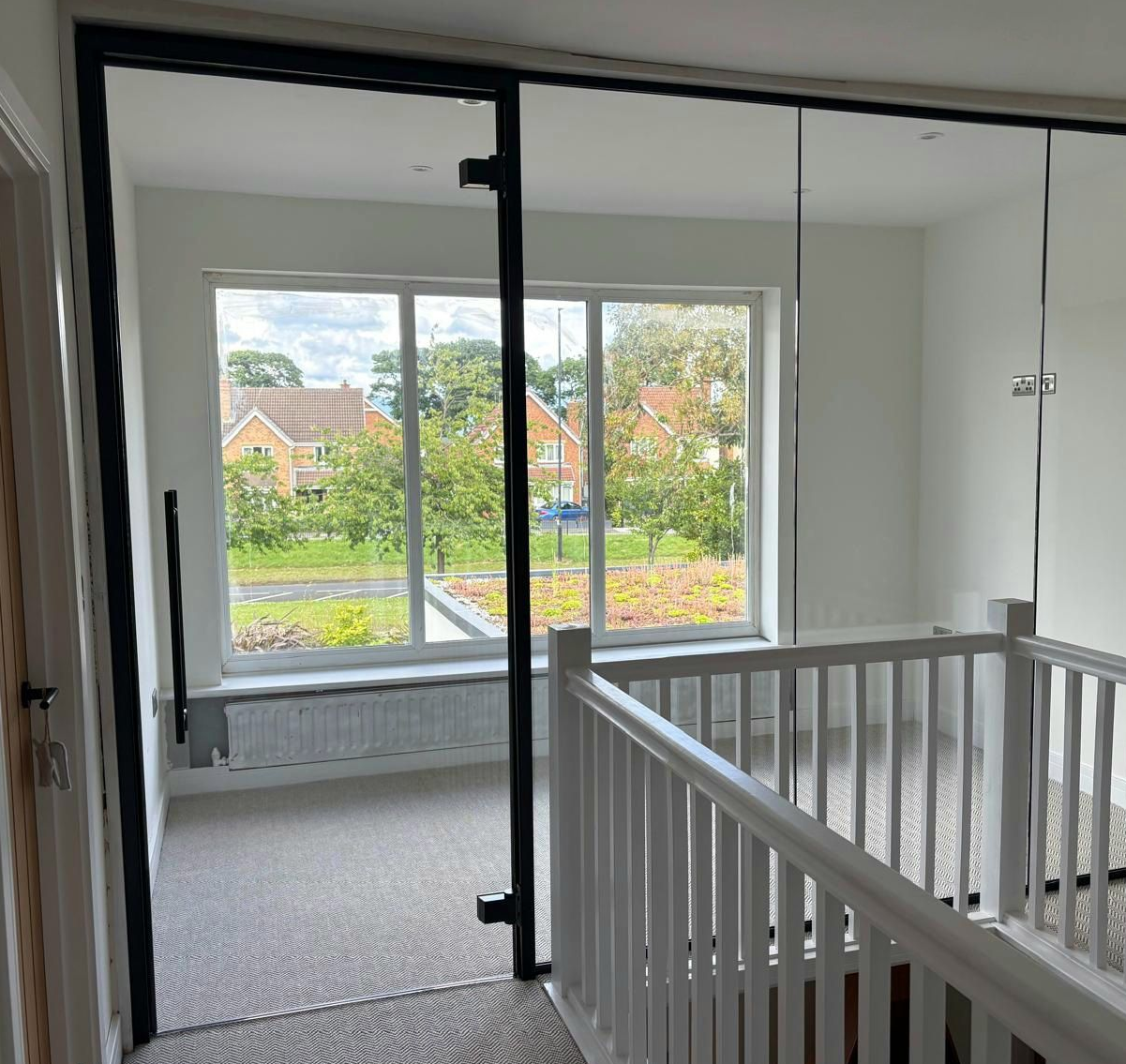 Home glass office partition with glass door installed using subtle black dry joints between glass panels 