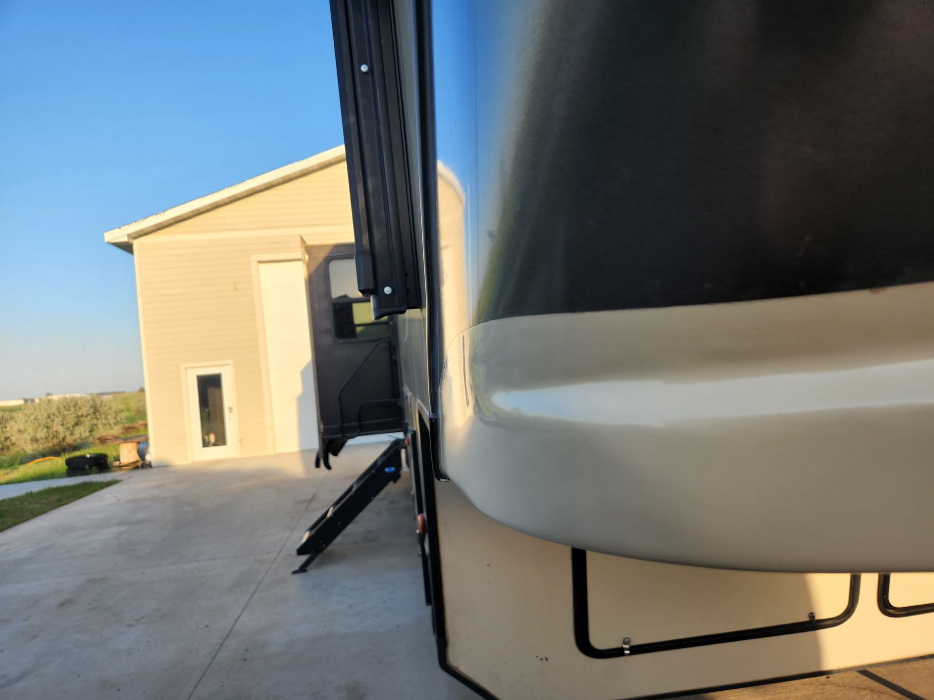 Close-up of a black-and-white RV parked beside a beige building on a sunny day