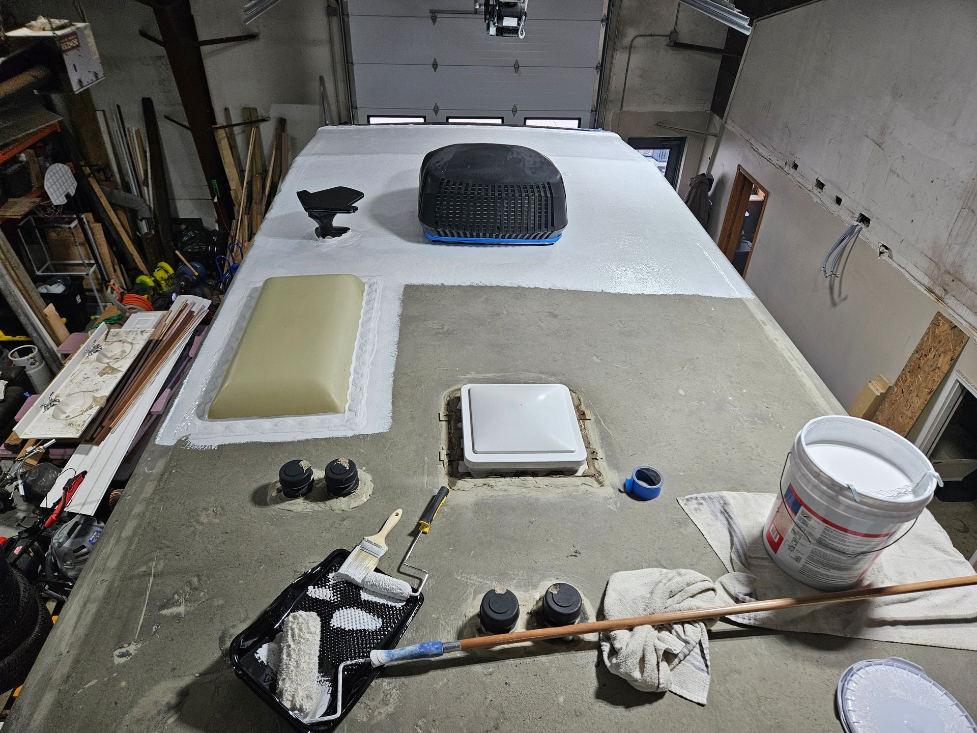 Garage floor with a white work surface, tire, tools, and painting supplies laid out for a project