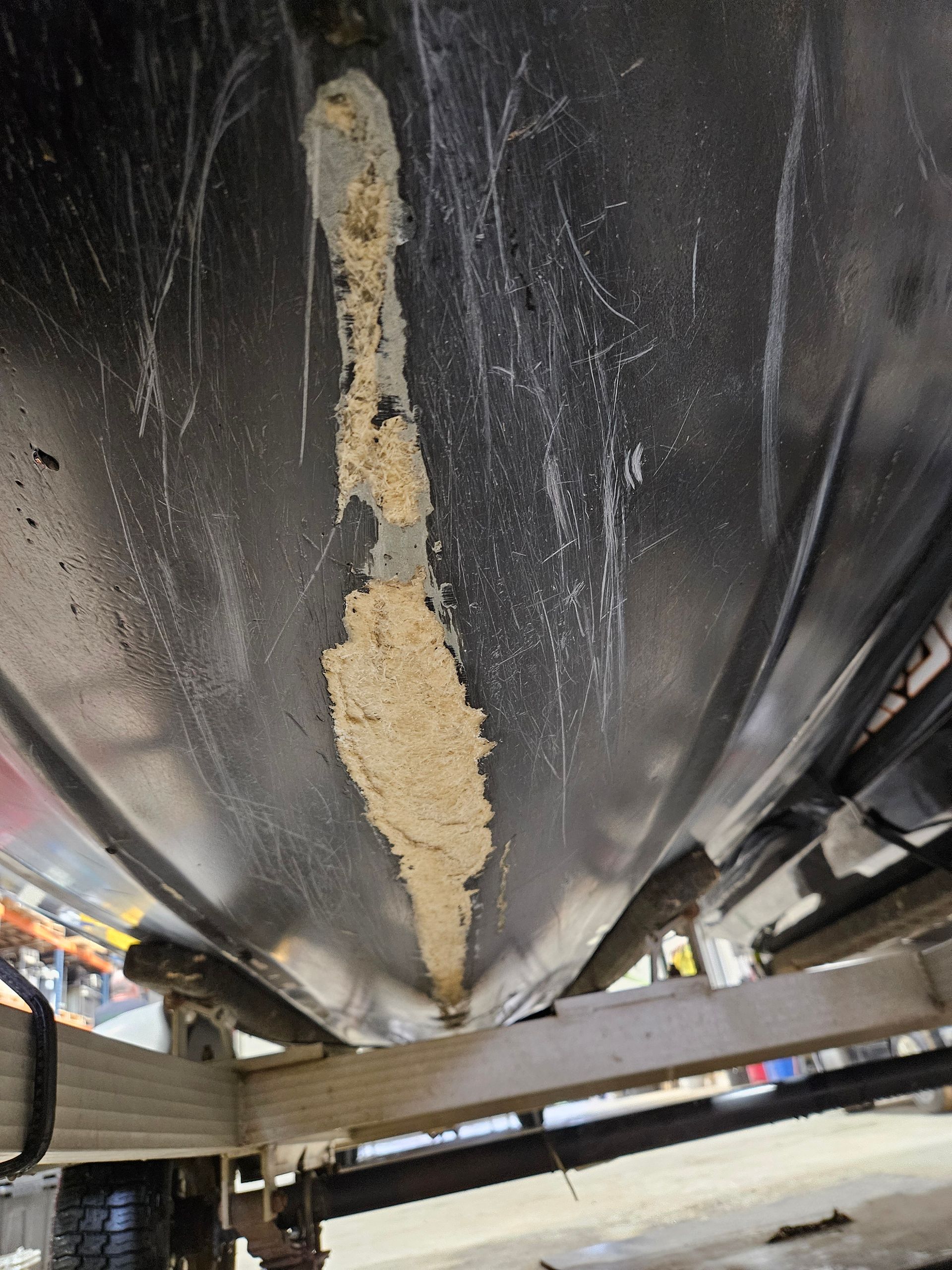 Close-up of a large black tank or hull with a beige scraped, damaged vertical strip underneath