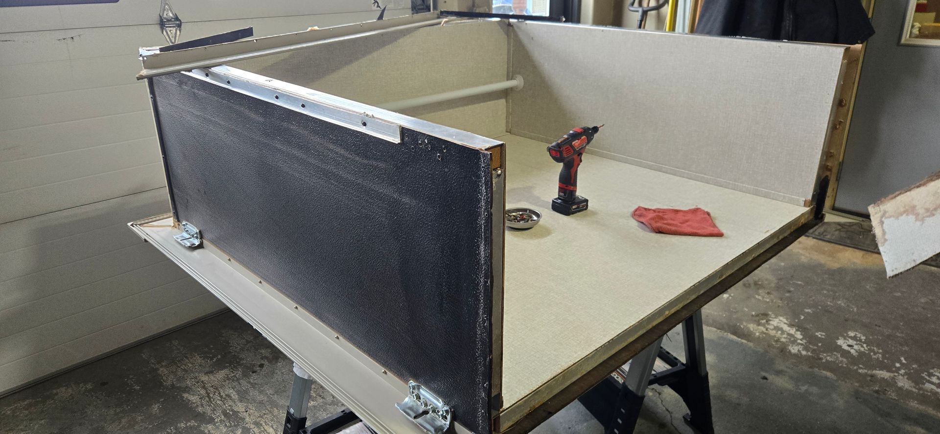 Workbench with beige tabletop, black side panel, and a red power drill in a workshop