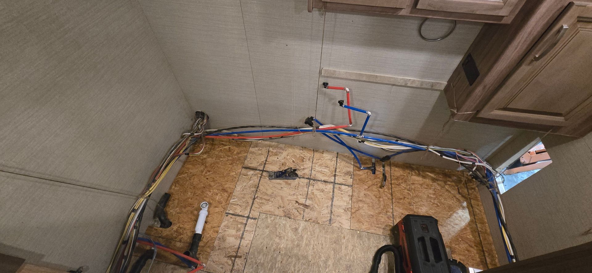 Small room with exposed insulation, wiring, and wooden floor framing under construction