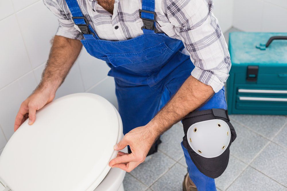 Plumber Installing Lid on Toilet in The Bathroom — DFW Airport, TX — Pipeline