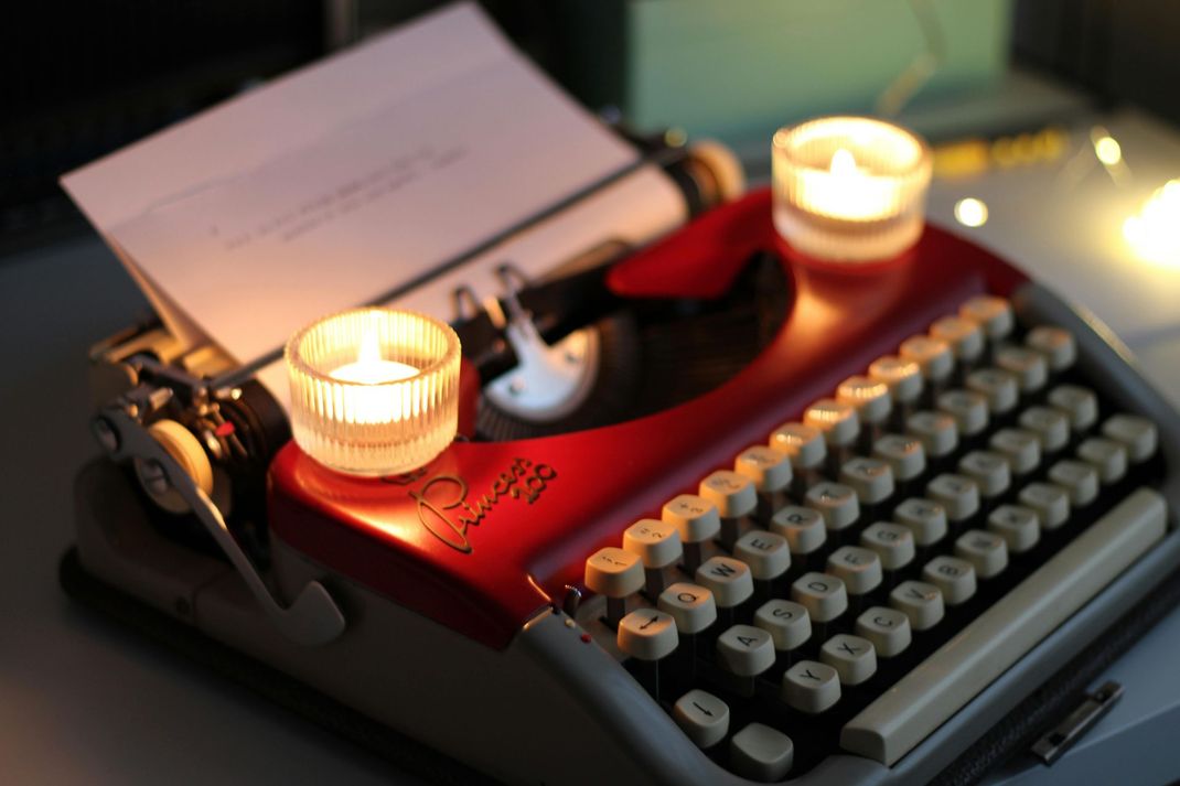 Old fashioned typewriter with small candles on it.