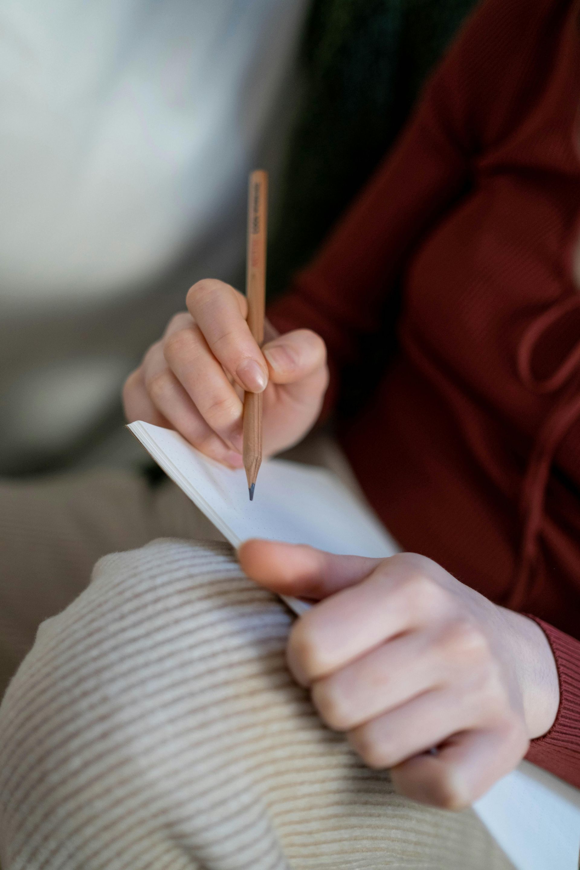Hand holding a pencil and writing on a tablet.