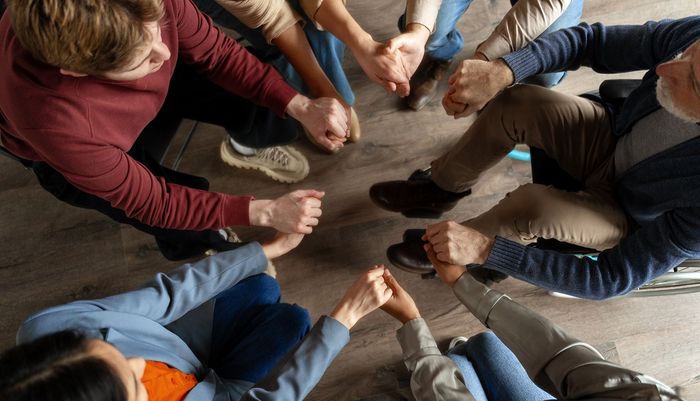 Group of people in a circle holding hands, indoors.