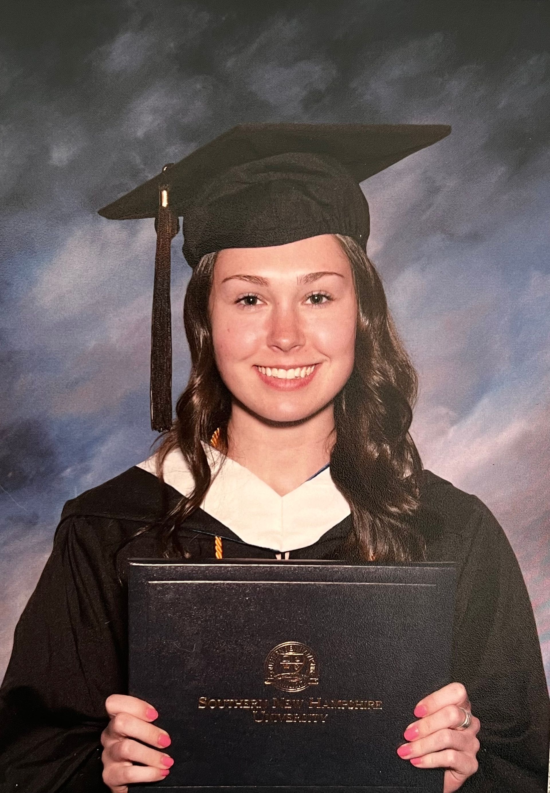 Two children in pink outfits and pom-pom headbands holding hands in front of a blue wall.