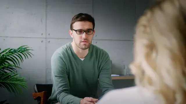 A woman with a backpack is walking up a rocky path in the mountains.