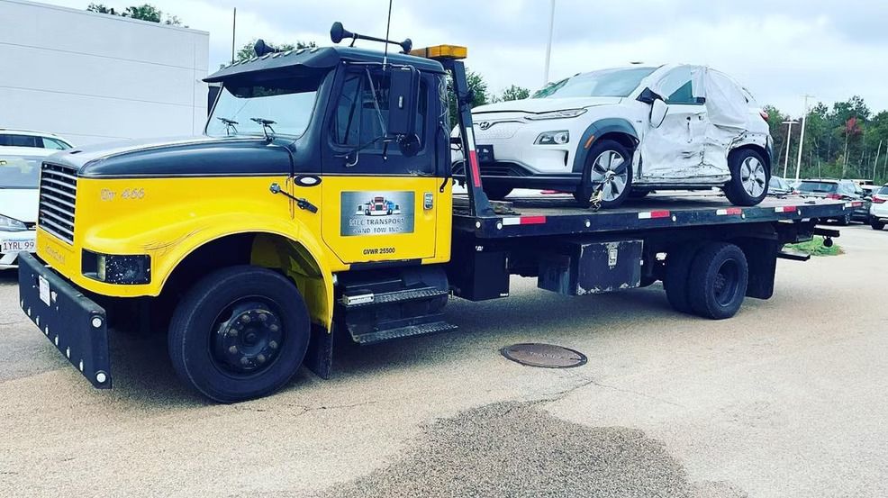 A yellow tow truck is towing a white suv.