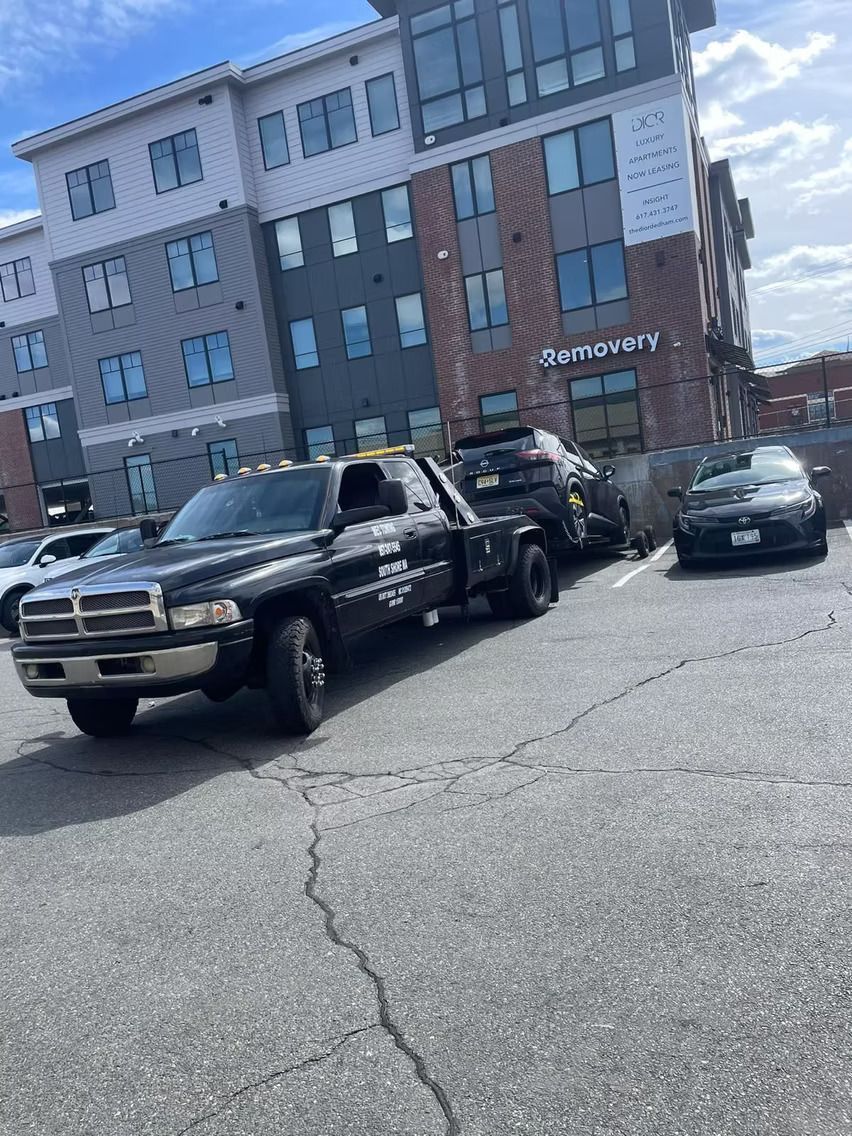 A tow truck is parked in a parking lot in front of a building.