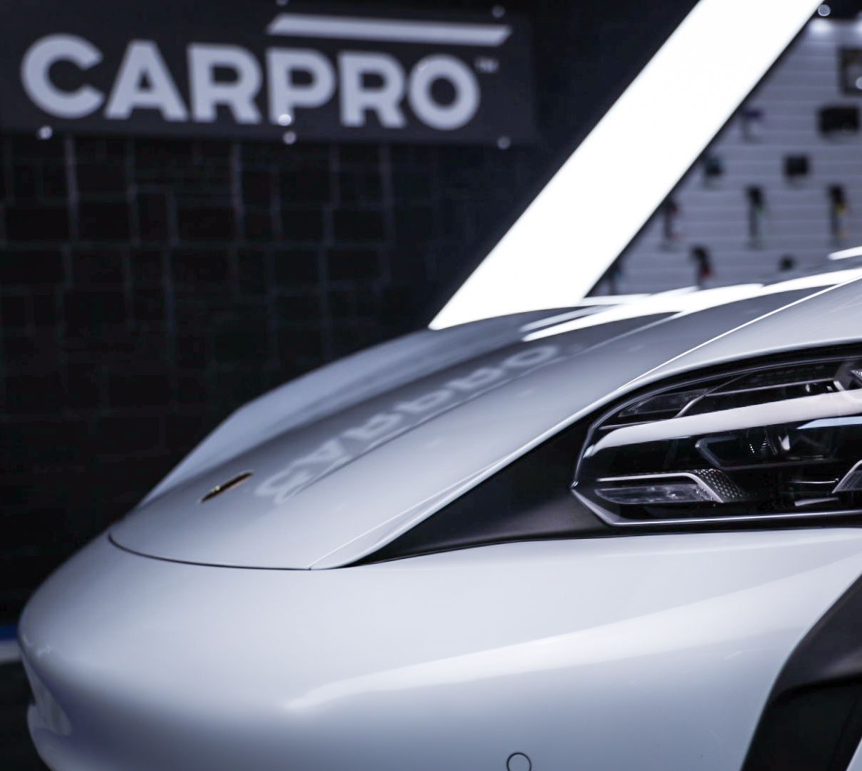 A white car is parked in front of a carpro sign