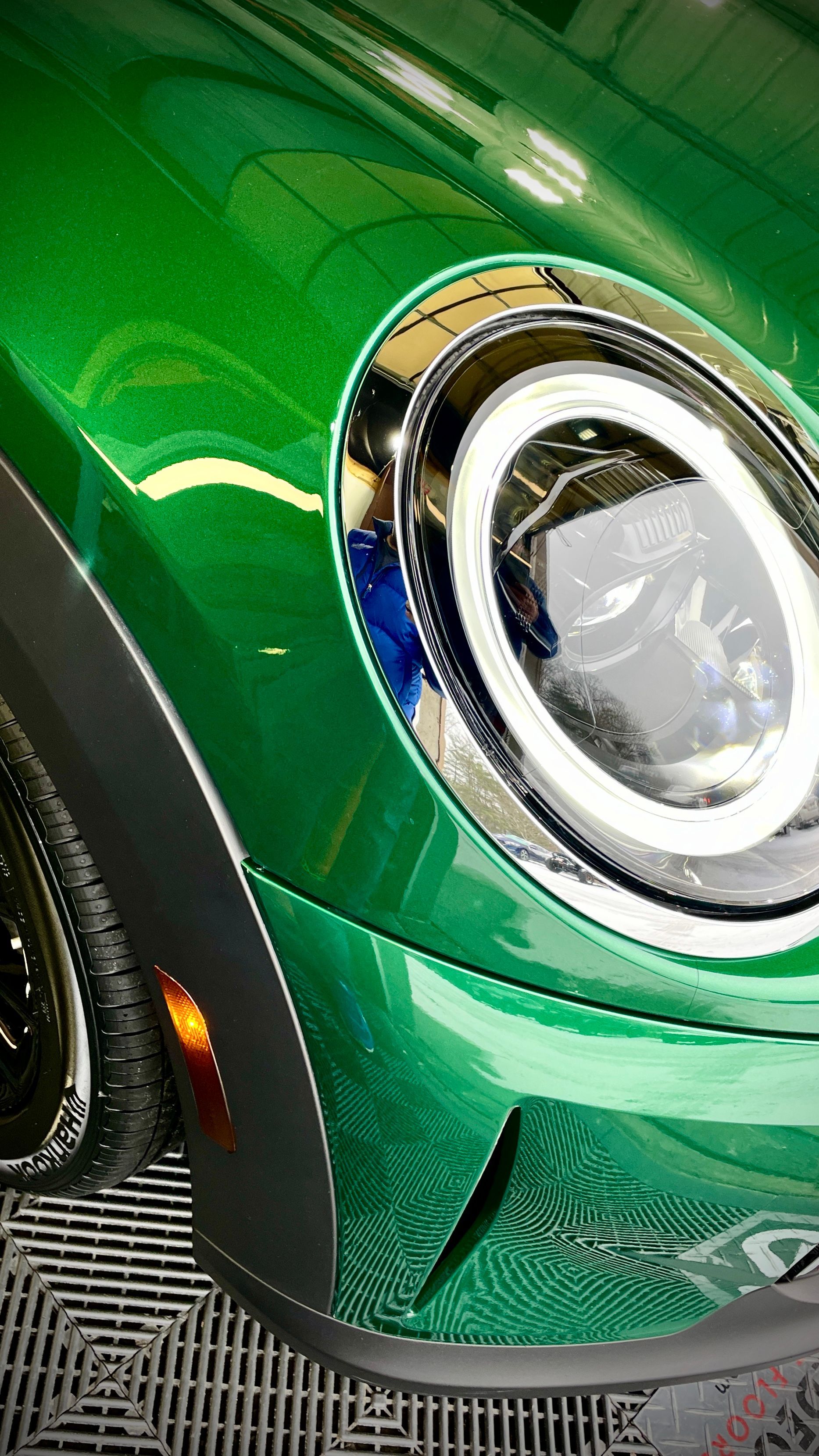 A close up of a green car 's headlight in a garage.