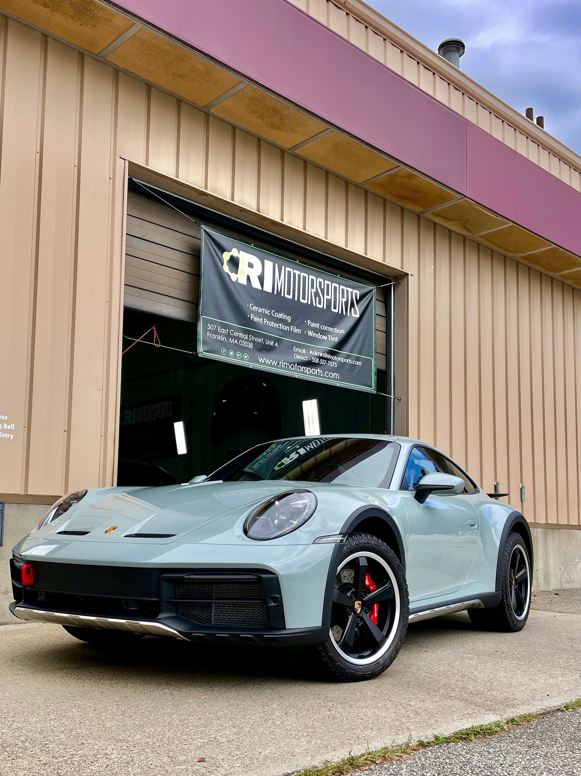 A porsche 911 turbo s is parked in front of a building.