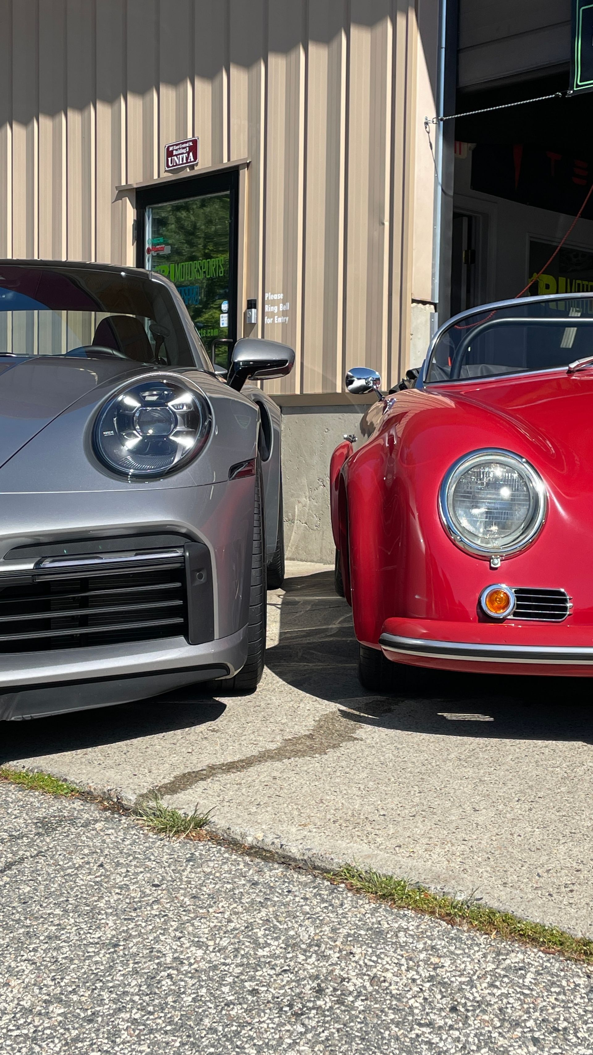 Two sports cars are parked next to each other in front of a building.