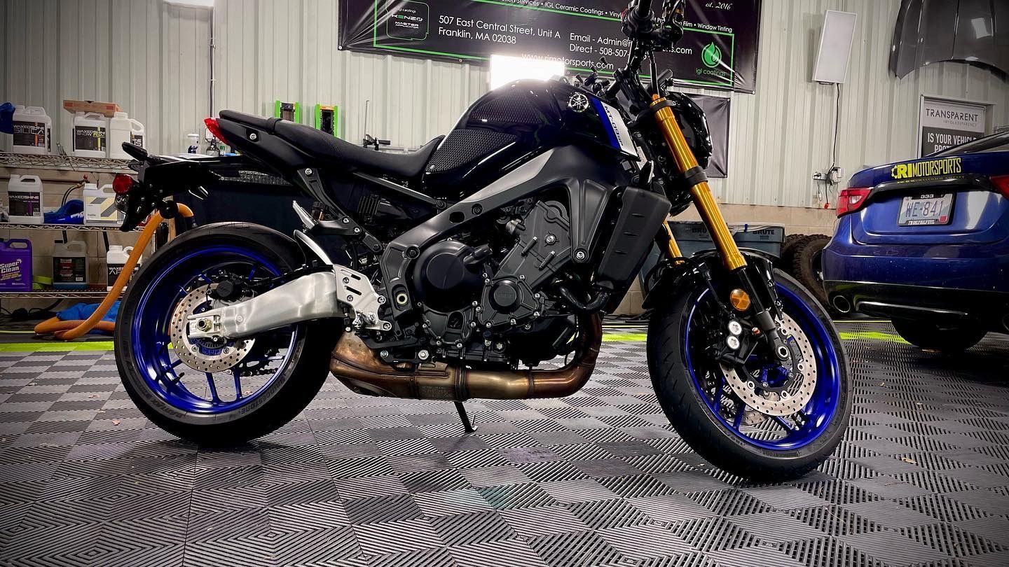 A motorcycle is parked in a garage next to a car.