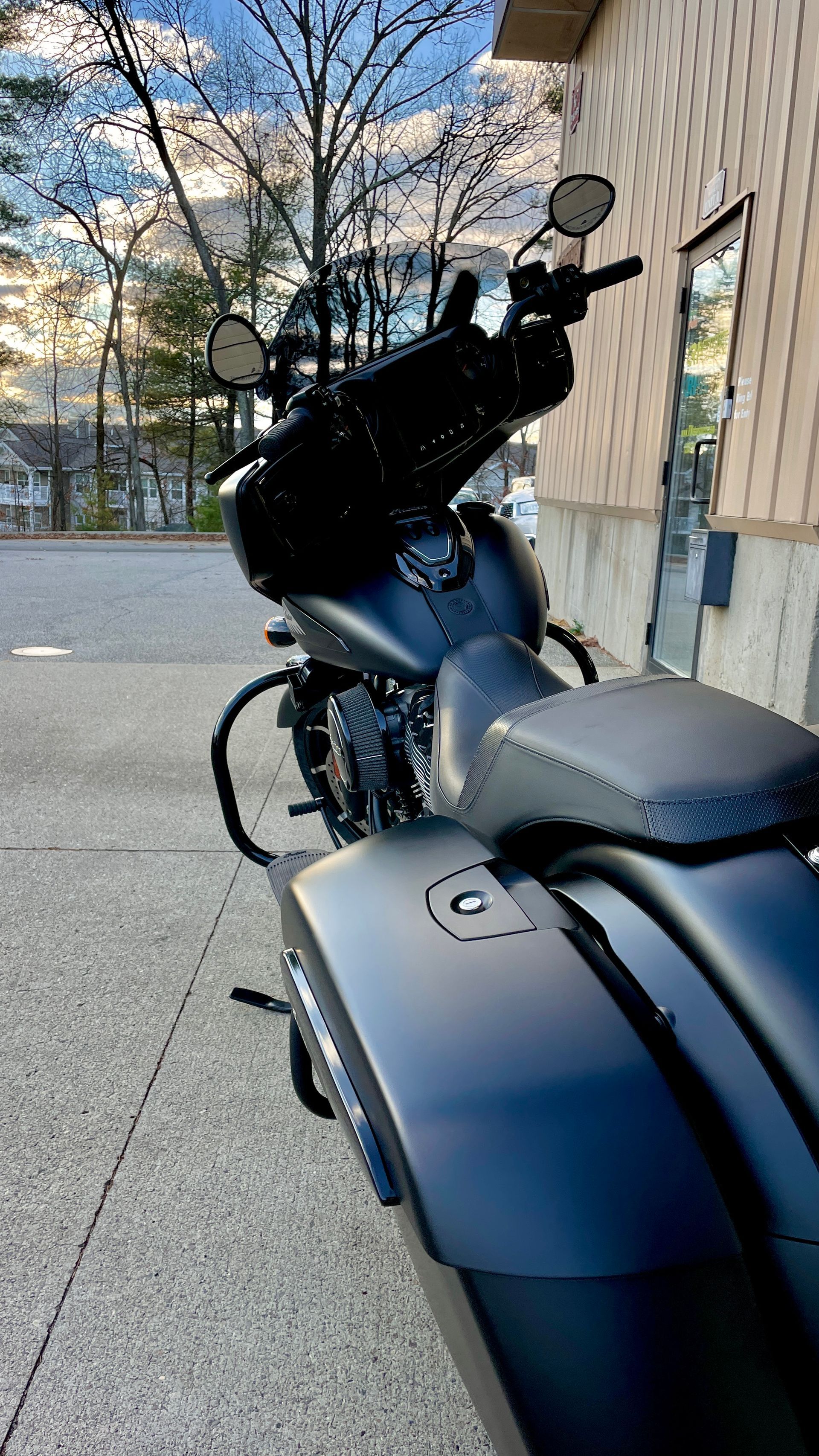 A black motorcycle is parked on the sidewalk in front of a building.