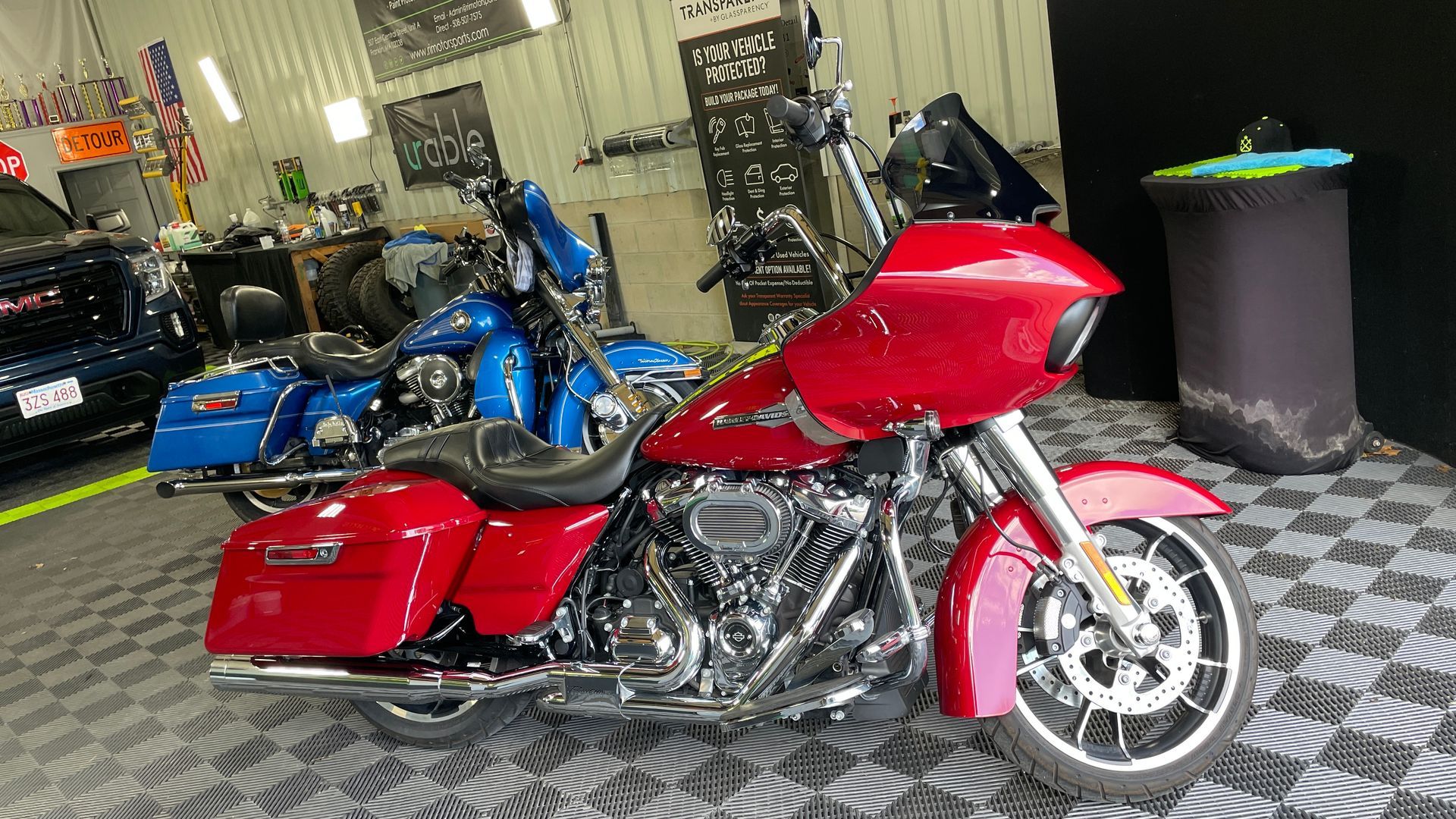 A red motorcycle is parked in a garage next to blue motor cycle