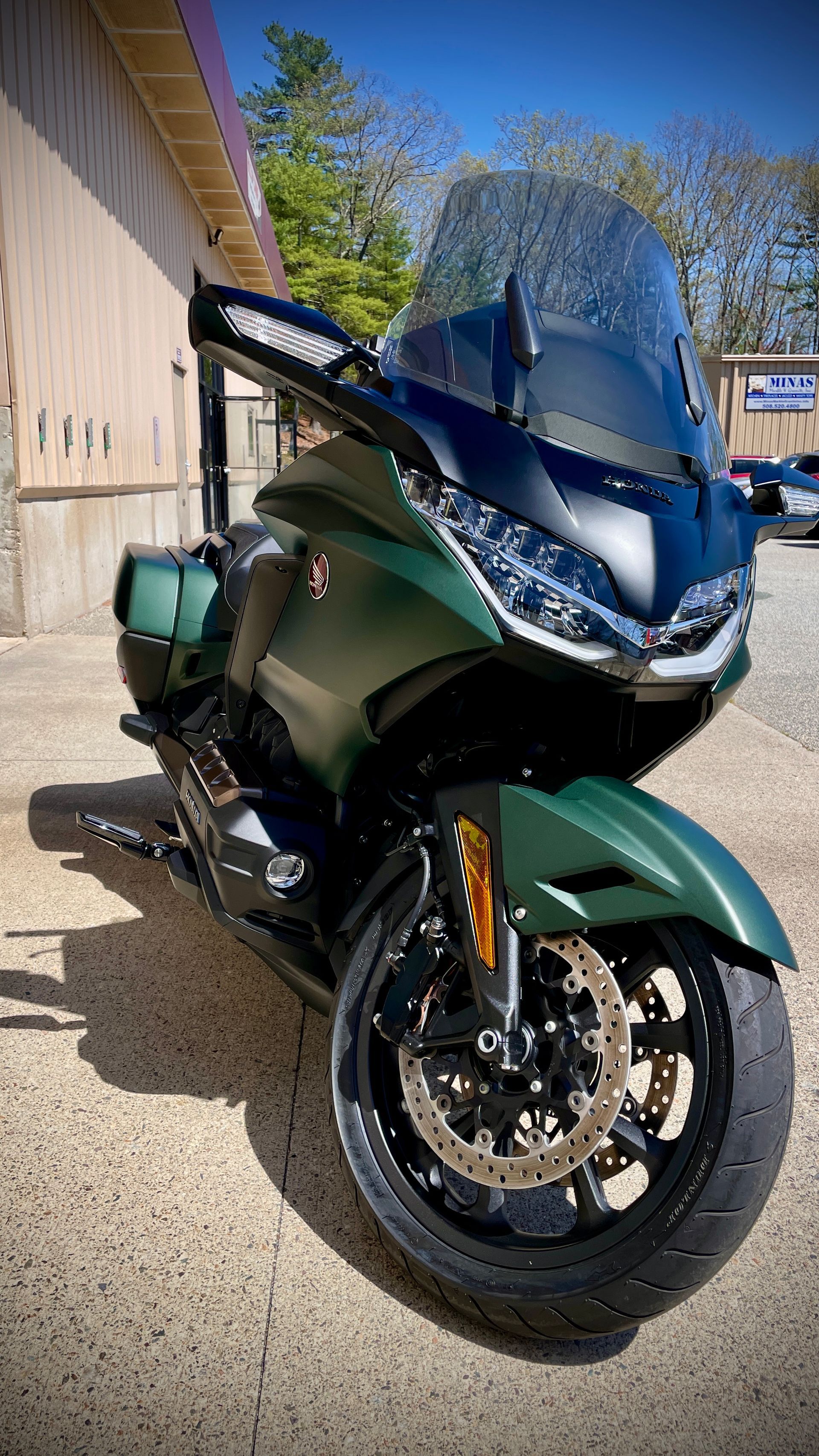 A green motorcycle is parked in front of a building.
