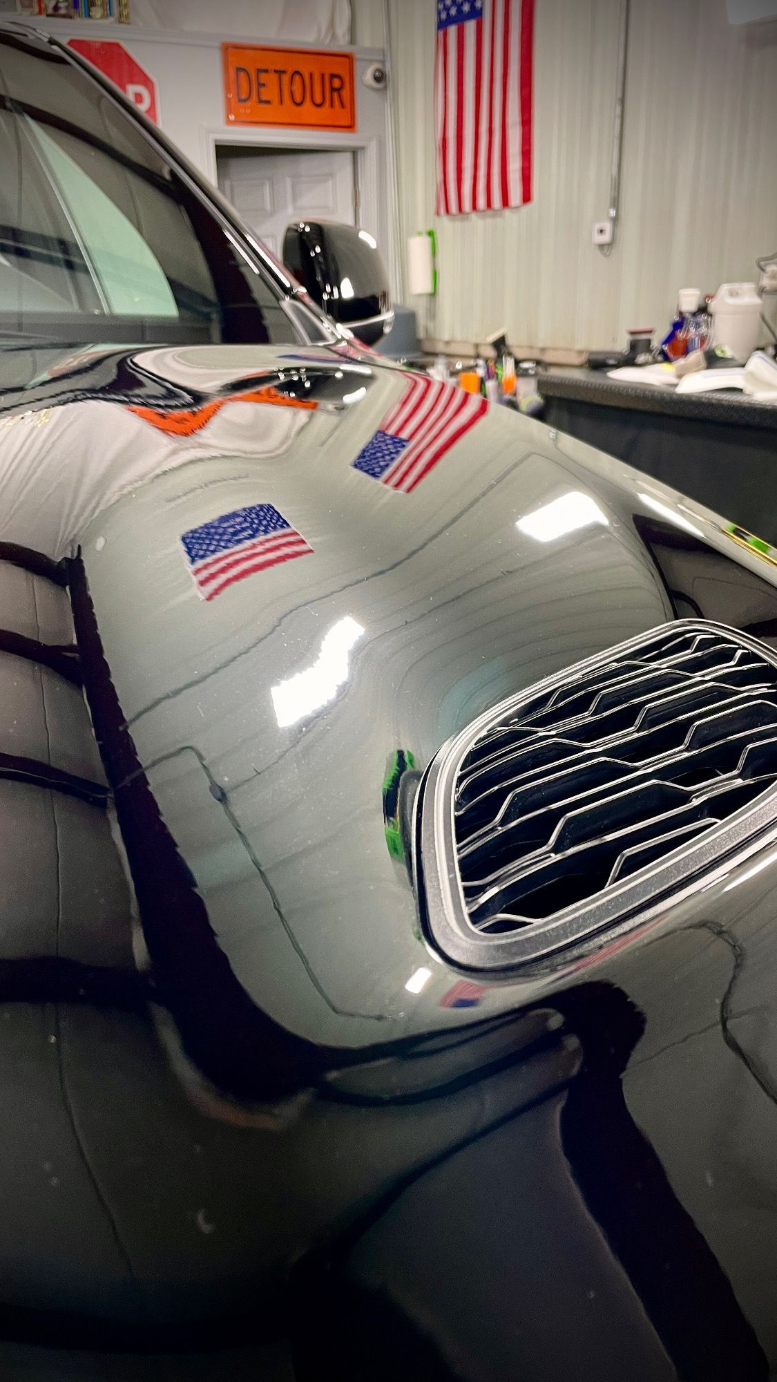 A car with american flags on the hood is parked in a garage.