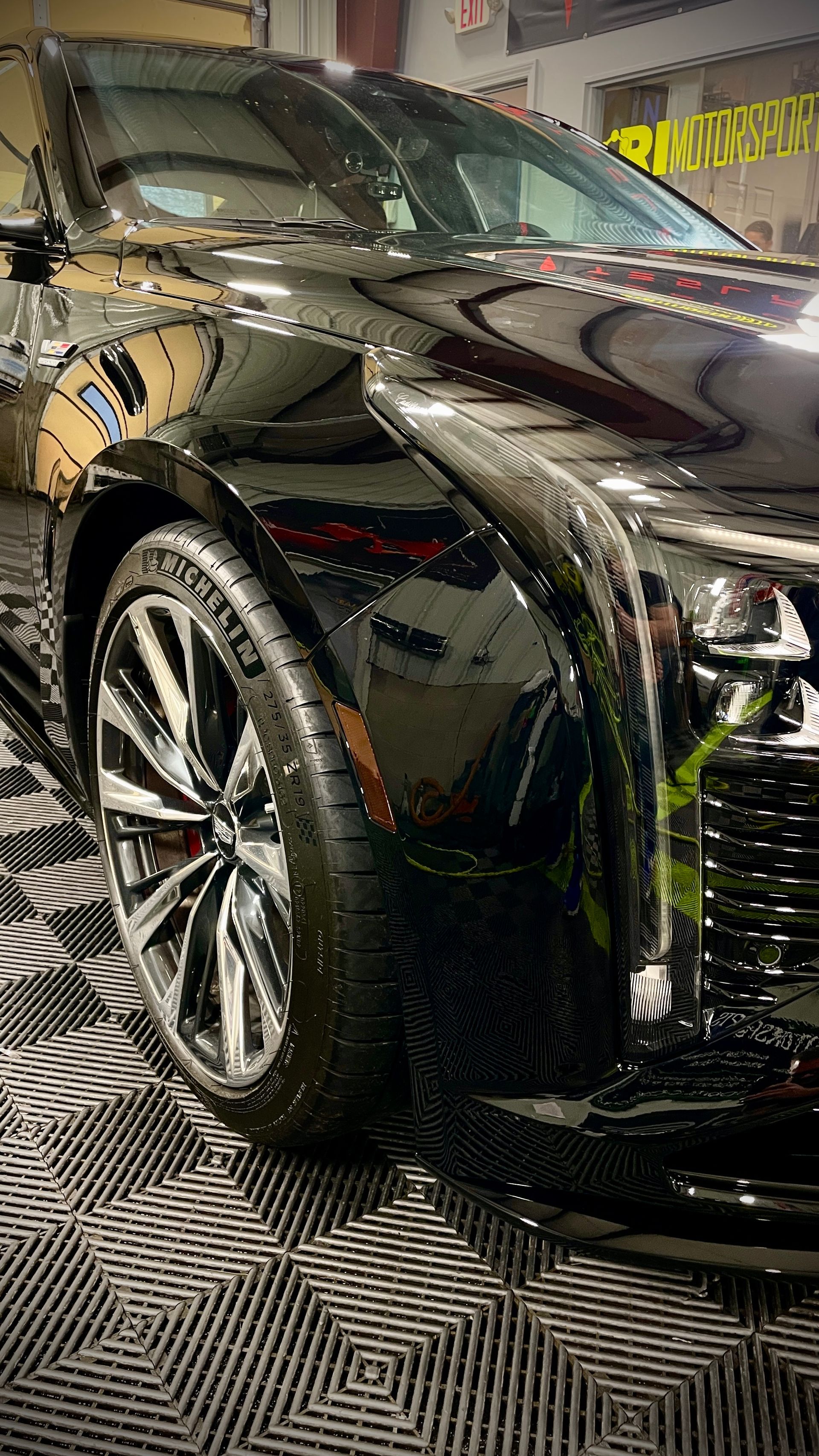 A black car is sitting on a tiled floor in a garage.