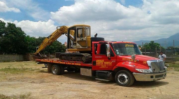 Una grúa roja con una excavadora amarilla en la parte trasera.