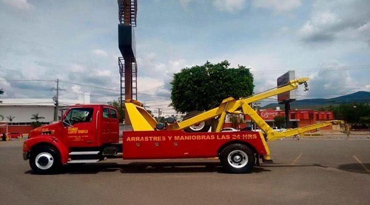 Una grúa roja y amarilla está estacionada al costado de la carretera.