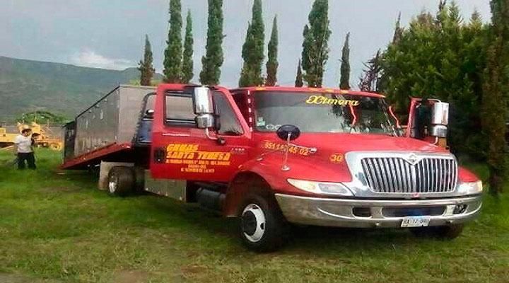 Una grúa roja está estacionada en un campo de hierba.