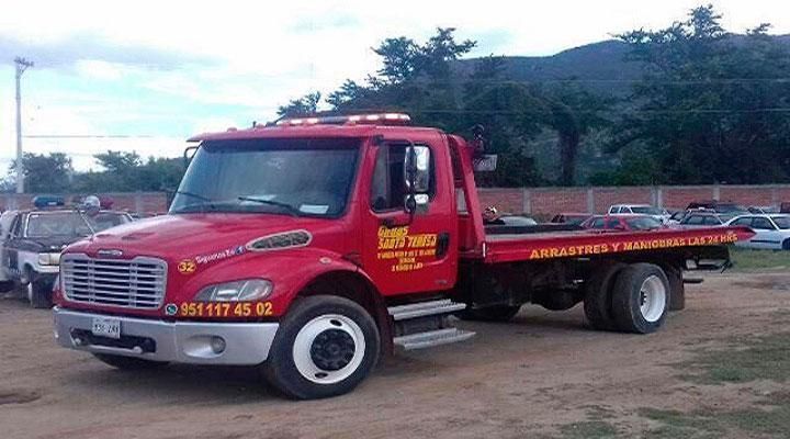 Una grúa roja está estacionada en un campo de tierra.