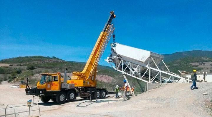 Un camión amarillo con una grúa acoplada está levantando un gran objeto blanco.