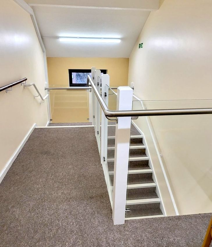 Pant Gwyn property interior staircase with steel posts and railing. Glass balustrade installed by Swansea Glass Balustrades.