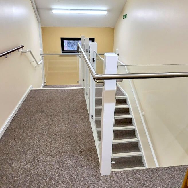 Pant Gwyn property interior staircase with steel posts and railing. Glass balustrade installed by Swansea Glass Balustrades.