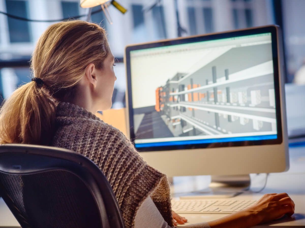 Swansea Glass Balustrades employee working on 3D architectural rendering. Indoors, focused, ponytail.