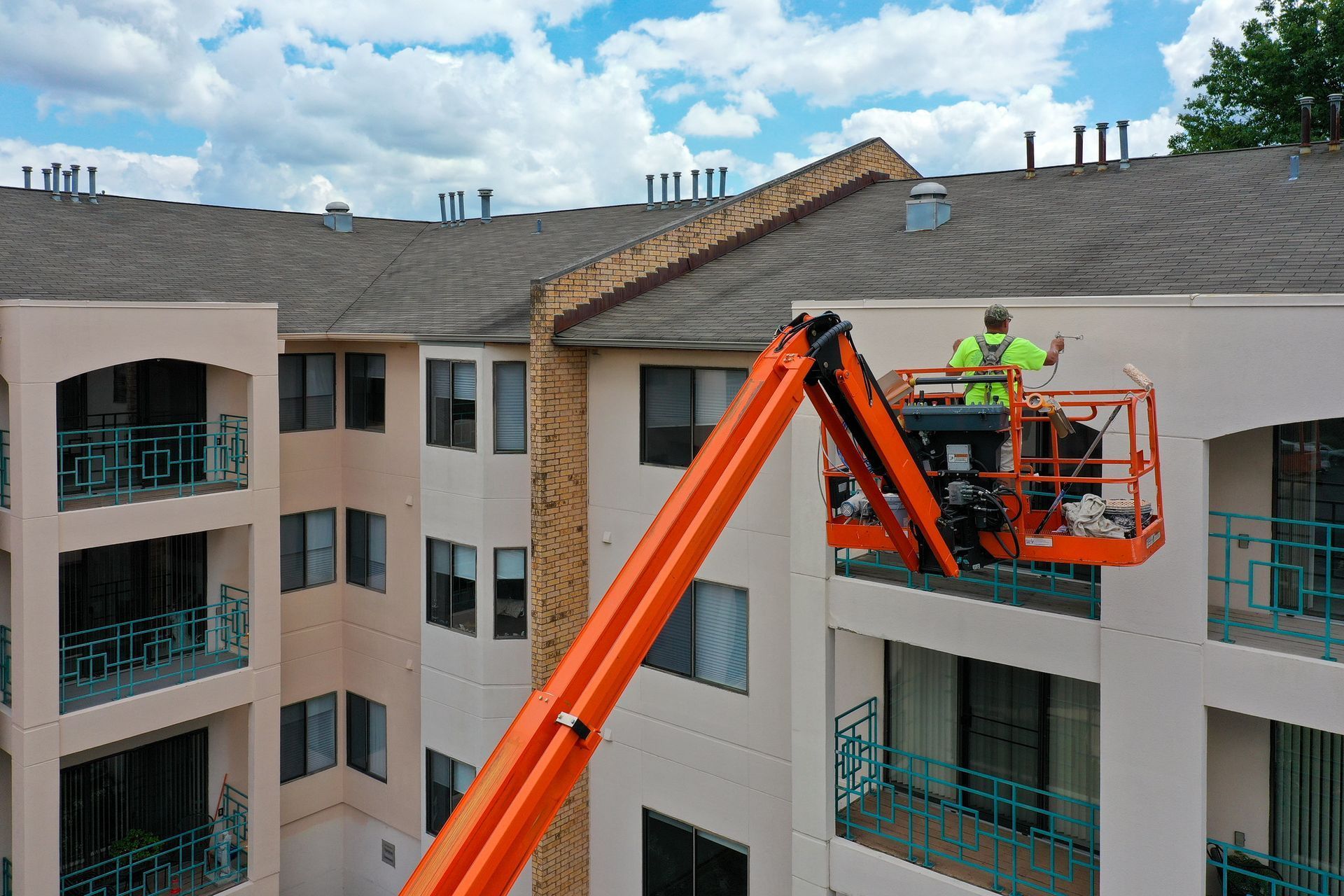 A man is standing in a crane on the side of a building.