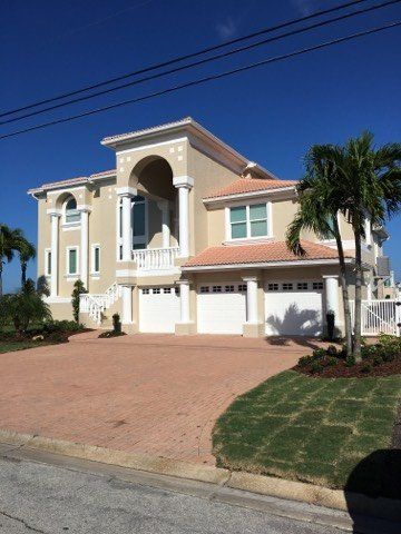 A man is painting a window on the side of a house.