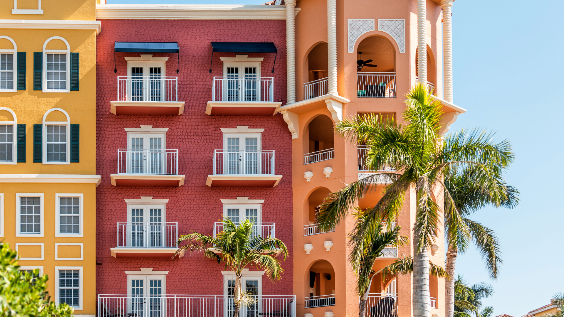 A red and yellow building with a palm tree in front of it.