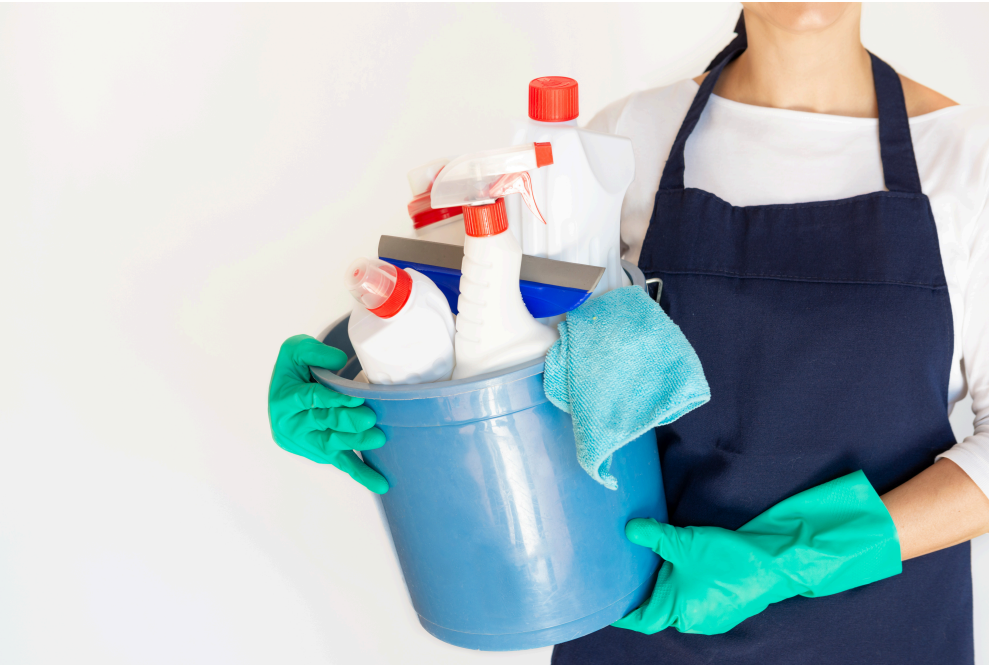 Cleaner holding bucket full of cleaning supplies with cleaning gloves.