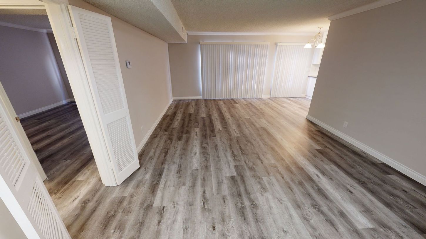 Interior view of a room with wood-look flooring, white walls, and a closed door on the left.