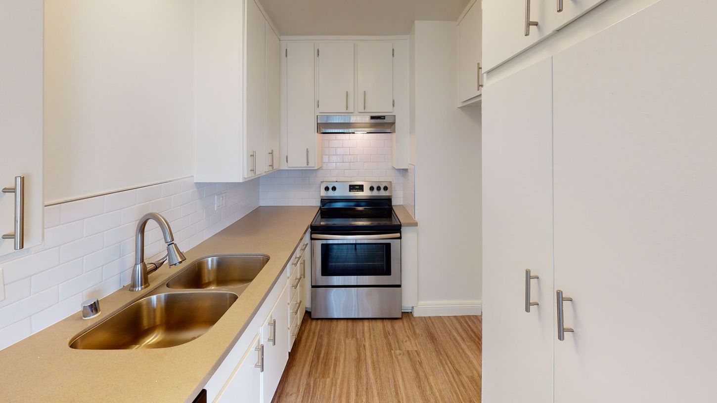 White kitchen with stainless steel appliances, cabinets, and light-colored countertops.