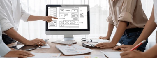 People at table looking at computer screen with design prototype.